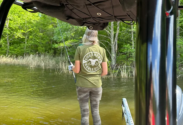 View from under the boat canopy toward a woman fishing on the bow
