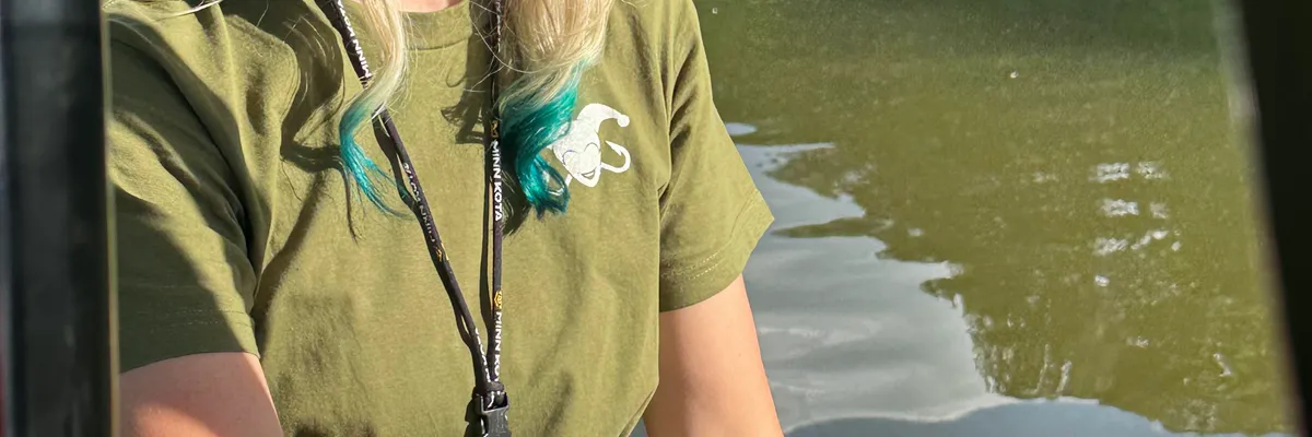 Gina wearing a Southern Harlequin cap at the helm of her boat